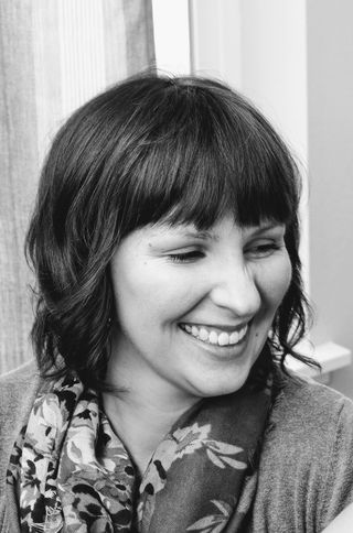Portrait of Susi Forshey smiling, wearing a floral scarf.