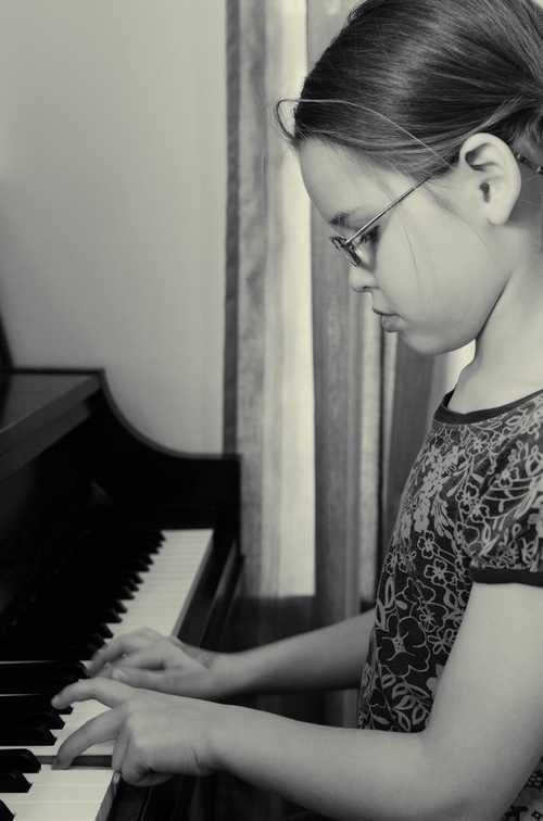 Young lady with glasses playing the piano.